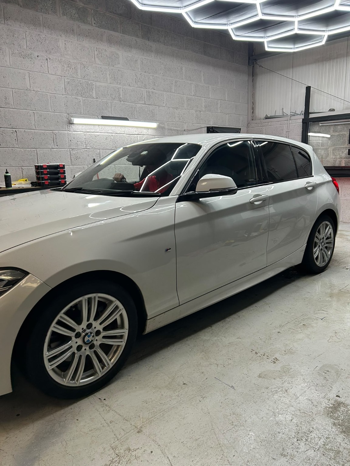 White BMW with professionally tinted windows inside the Cre8Customs workshop